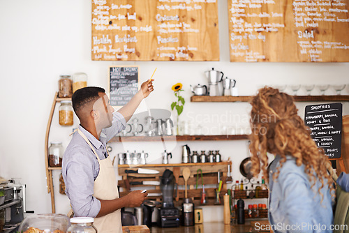 Image of Coffee shop, customer and barista with pointing at menu for purchase, decision and service at restaurant. Waiter, small business and woman at cafe with options, discussion and choice for lunch order