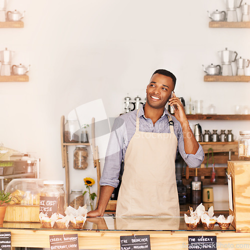 Image of Planning, smile and phone call with black man in coffee shop for communication, networking or service. Cafe, restaurant and thinking with happy young small business owner or vendor working in bakery