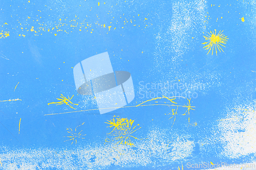 Image of Abstract yellow paint splatters on a vibrant blue background