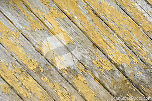 Image of Close-up view of weathered wooden boards with peeling yellow pai