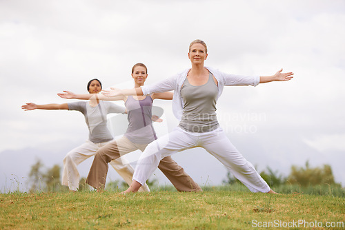 Image of Group, yoga and women in warrior pose outdoor for healthy body, exercise and fitness. Park, virabhadrasana and people in nature for balance, stretching and friends practice together for wellness