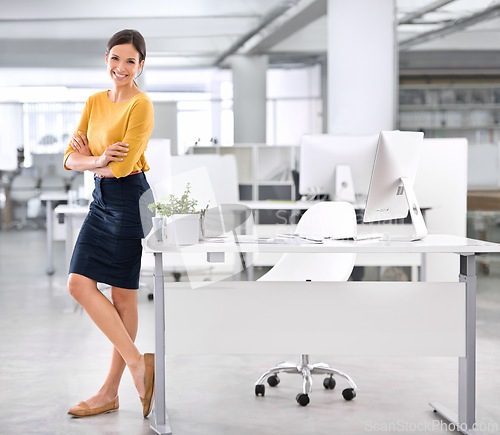 Image of Portrait, business and woman with arms crossed, standing at her desk and professional in a workplace. PR agency, employee and consultant with startup, pc and office with entrepreneur and computer