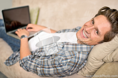 Image of Man, portrait and laptop on sofa or relax for online browsing at home or streaming movie, internet or scrolling. Male person, face and couch at house in London for weekend, resting or entertainment