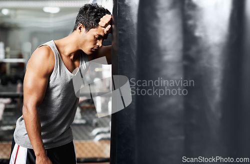 Image of Gym, fitness and tired with man and punching bag, low energy and performance mistake or disaster. Sports, fatigue or boxer exhausted by intense body workout, challenge or fighting practice burnout