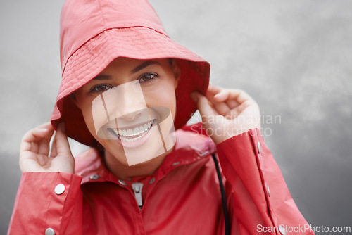 Image of Happy woman, portrait and rain jacket with hat for weather, cloudy sky or winter season in outdoor storm. Face of female person with red waterproof coat and smile for protection, fog or cold overcast