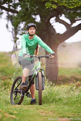 Image of Woman, sports and fitness with bicycle on field for outdoor cycling, workout or cardio exercise in nature. Female person, athlete or cyclist in forest for off road training on green grass or trail