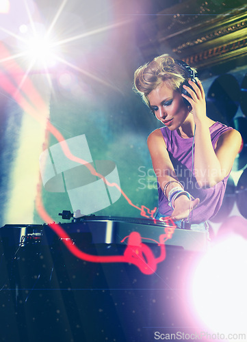 Image of Woman, dj and turntable with headphones for music on stage with lens flare, mixing and gig at rave party for entertainment. Female sound mixer, artist and musician with record player for playlist