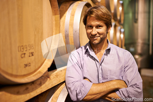 Image of Portrait, smile and wine tasting with a man in the cellar of a distillery on a farm for the production of alcohol. Glass, industry and barrel with a happy male farmer or sommelier for quality control