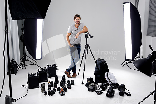 Image of Photographer, happy or lighting with equipment in studio for career, behind the scenes or camera. Photography, guy and confidence with electronics, portrait or shooting gear for photoshoot or passion