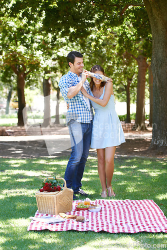 Image of Love, picnic and surprise with couple in park for romance, bonding and summer vacation. Happiness, commitment and relax with man and blindfold woman in nature for date, support and relationship