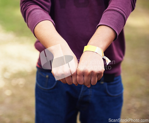 Image of Closeup, hands and outdoor with person, music festival and bracelet for an event and partying. Vacation, outside and fist with band and weekend break with summer and holiday with sunshine and ribbon