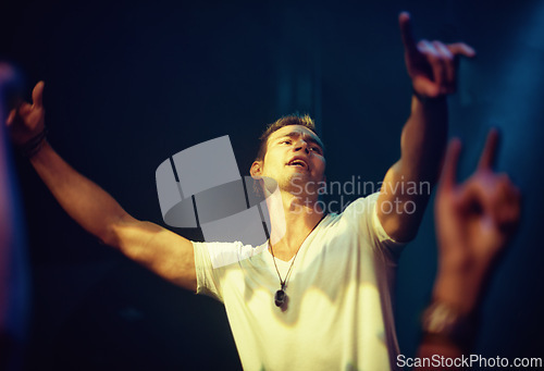 Image of Dance, music and night with man at concert for performance, energy and rock festival. Party, nightclub and event with excited male person and arms raised for musician, disco and rave culture