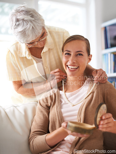 Image of Elderly mother, necklace and portrait of woman with present, gift and surprise in living room. Family, love and happy daughter with mom giving pearls on sofa for celebration, birthday and bonding