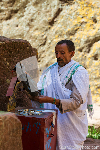 Image of Man counts collected funds from the faithful outside St. George Church, Lalibela Ethiopia