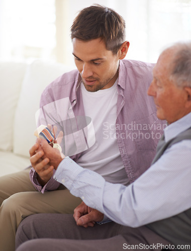 Image of Elderly, man and son or medal on sofa with war badge, pride and honor for military hero in living room of home. Senior, veteran and retired soldier with medallion for service in army with happiness