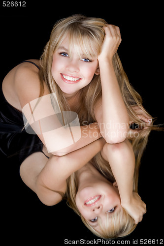 Image of The young smiling blonde and her reflection in a mirror