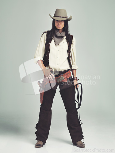 Image of Woman, cowgirl and portrait in studio for fashion costume with confidence on grey background, weapon or outlaw. Female person, whip and hat with mockup space in Texas for dress up, old west or rodeo