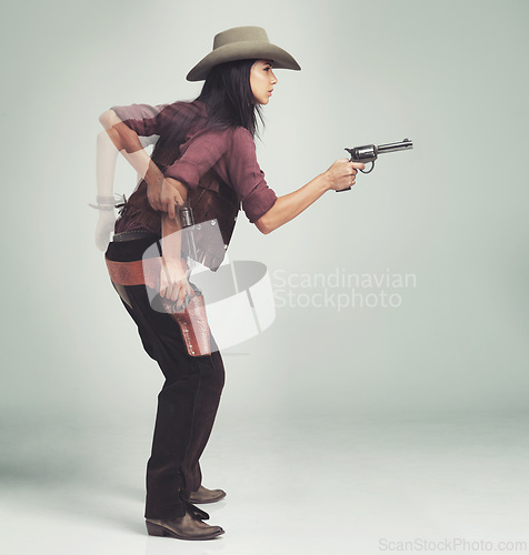 Image of Western, cowboy and woman with gun in studio for motion, speed and shooting with standing ready. Female person, weapon and serious expression with pistol for character, halloween and costume design