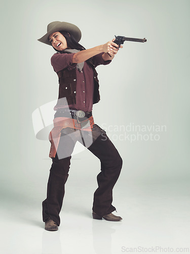 Image of Western, woman and cowboy with gun in studio for fashion, nervous and scared to shoot on grey background. Female person, vintage and outlaw with pistol for wild west, costume and character with hat