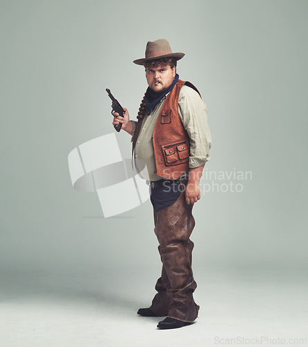 Image of Portrait, man and cowboy with a gun, serious and proud person on white studio background. Face, model and guy with pistol or firearm with danger or warning with Halloween costume, confidence or Texas