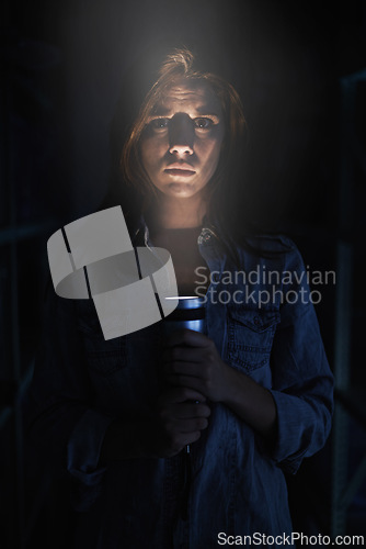 Image of Portrait, horror and torch for light with woman on black background to hide from fear, panic or terror. Stress, depression and mental health with scared young person in dark for danger or violence