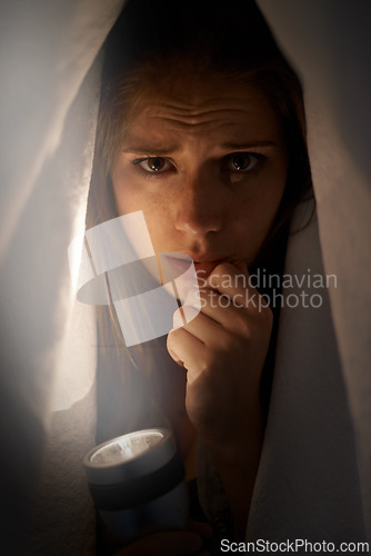 Image of Woman, flashlight and portrait with blanket for mental health, horror or anxiety. Young person and scared or sad with depression, ocd or horror for financial crisis, stress and disappointment