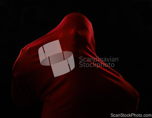Image of Scary, horror and person trapped in fabric for art and drama on black background in studio. Suffocating, fear and model stuck in cloth as demon, monster or ghost with terror for creative aesthetic