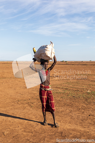 Image of Dasanesh man carries bag on his head, Omorate, Omo Valley, Ethiopia