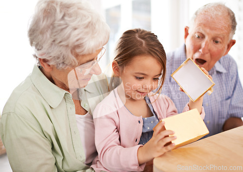 Image of Grandparents, child and open gift box, surprise for birthday with celebration for special event and family at home. Old people with young girl, unboxing and wow reaction for present with happiness