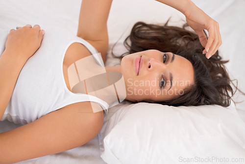 Image of Portrait, relax and woman on bed in home for peace or resting in the morning alone in house. Face, healthy and young person in bedroom on comfortable pillow, wakeup and calm in apartment in Australia