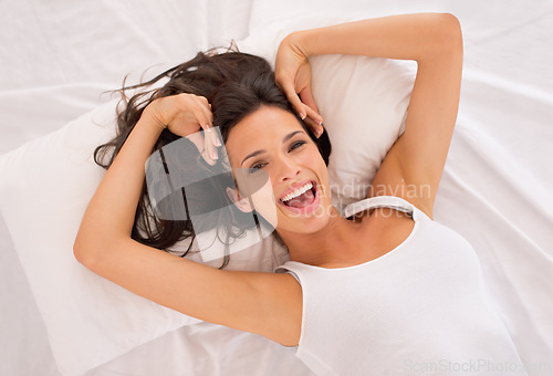 Image of Portrait, happy and top view of woman on bed in home to relax or resting in the morning. Face, above and excited person in bedroom on comfortable pillow, wakeup or laughing in apartment in Australia