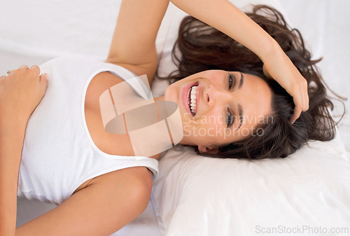 Image of Portrait, smile and top view of woman on bed in home to relax or resting in the morning. Face, above and happy person in bedroom on comfortable pillow, wakeup or laughing in apartment in Australia