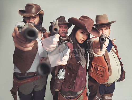 Image of Western, cowboy and gun with point in studio for wild west, criminal or outlaw on grey background. Band of people, portrait and face with pistol with shoot gesture for aim, weapon or fire with danger