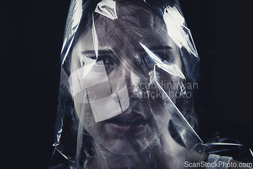 Image of Plastic, woman and bag on face with scary drama in studio, dark background or afraid of death. Suffocation, murder and girl with fear from crime, victim and trapped in trash, garbage or pollution