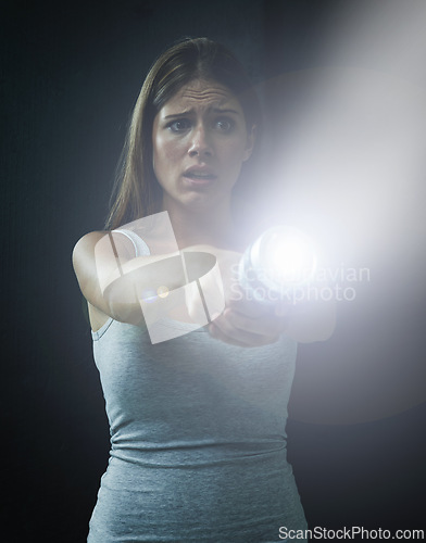 Image of Woman, fear and horror or flashlight for search in studio, anxiety and stress for risk in mystery. Female person, nervous and lamp in dark against black background, caution and danger on halloween