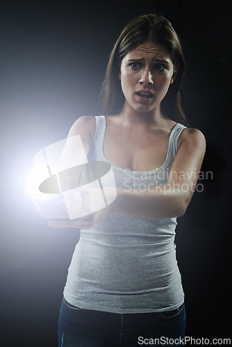 Image of Woman, fear and scared or flashlight for search in studio, anxiety and stress for risk in mystery. Female person, nervous and lamp in dark against black background, caution and danger on halloween