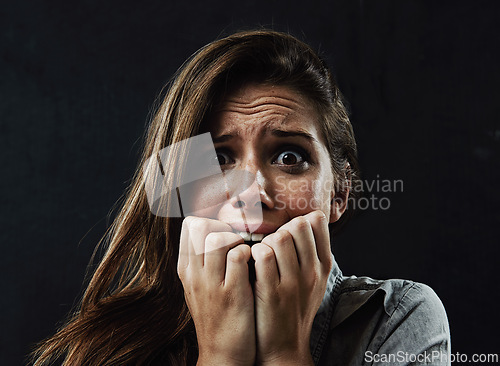 Image of Portrait, mental health and woman biting nails in studio on black background for reaction to fear or panic. Face, stress and horror with scared young person in dark for drama, nightmare or terror