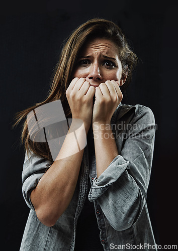 Image of Portrait, horror and woman biting nails in studio on black background for reaction to fear or terror. Face, anxiety and mental health with scared young person in dark for stress, phobia or nightmare