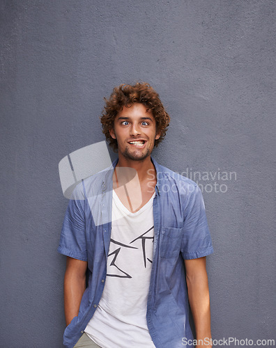 Image of Crazy, funny and portrait of young man by wall for comic, playful or comedy joke expression. Silly, goofy and face of confident male person from Colombia by gray background with mockup space.