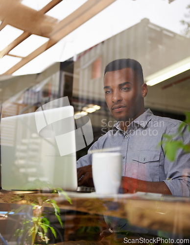 Image of African man, laptop and writing for reading, search and typing for work with coffee in workspace. Self-employed, freelance and male person with computer for internet, browsing and communication