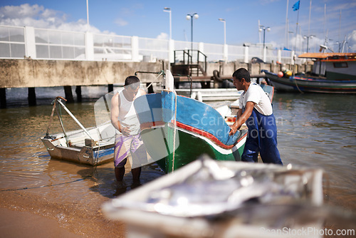 Image of Lake, boat and fishermen by water for fishing industry in sea by outdoor dock for small business. Teamwork, labour and male people working with vessel at ocean harbor, marina or pier by shipyard.