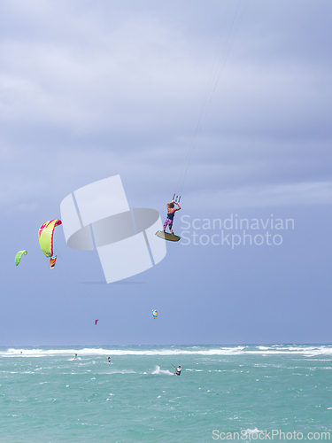 Image of Kiteboarding. Fun in the ocean. Extreme Sport Kitesurfing. Kitesurfer jumping high in the air performing triks during kitesurfing session.