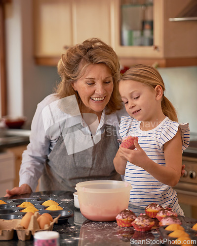 Image of Elderly woman, girl and smile for teaching, baking and bonding together at weekend in family home. Happy, senior citizen and child with cupcake, ecourage and icing for creative fun in kitchen