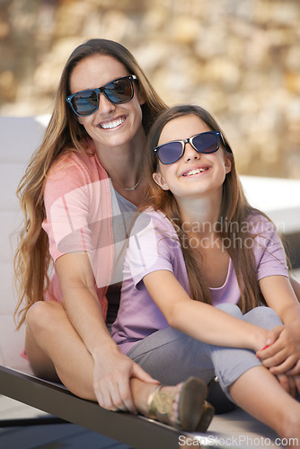 Image of Portrait, love and mother on vacation with daughter outdoor in sunglasses for summer, travel or holiday. Family, smile and mom hugging girl child on poolside deck chair for bonding, trip or getaway