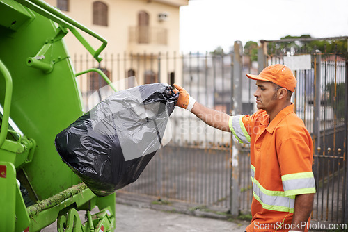 Image of Cleaning, waste management and garbage truck with man in uniform throwing black bag outdoor on city street. Job, service and trash with serious person working for sanitation or collection of dirt