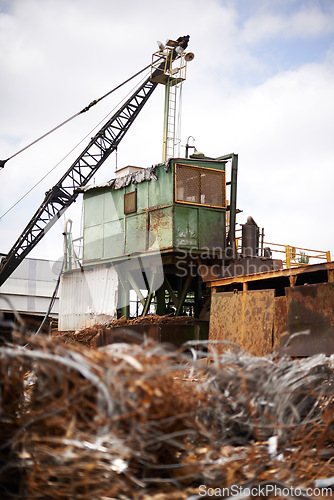 Image of Crane, machine and scrapyard for moving metal with sustainability, manufacturing or stop pollution. Vehicle, tractor and outdoor in junkyard, plant or ecology for iron, steel industry and environment