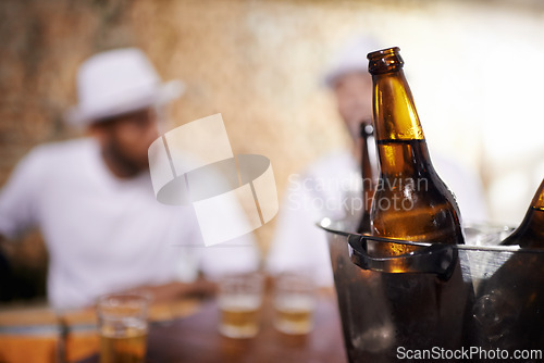 Image of Beer bottles, alcohol and beverages with men by bar, pub or nightclub for drinking, socializing or partying. Ciders, ice bucket or glasses on counter at tavern, lounge or restaurant for entertainment