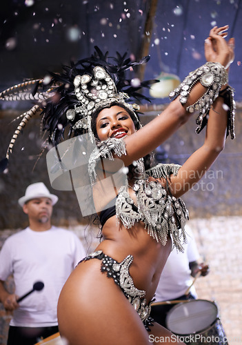 Image of Dancer, carnival and girl in performance with band, feather crown and pride for culture in low angle in night. Person, woman and stage at event, party and music for celebration in Rio de Janeiro