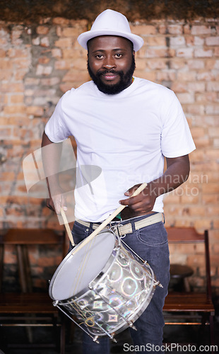 Image of Portrait, drums or carnival with a black man playing an instrument in a festival in Rio de Janeiro. Brazil, ready or party with a male musician, performer or artist banging on a drum to create a beat