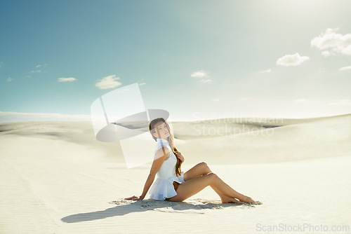 Image of Portrait, fashion and woman with vacation, sand and weekend break with dune, relax and getaway trip. Blue sky, person and girl with holiday and pose with adventure and outdoor with nature and desert